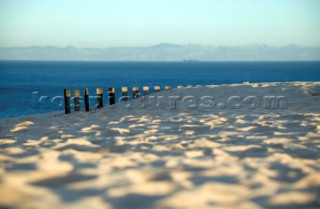 Sand dunes and fencing on a wind swept sandy beach in Tarifa, Spain, near Gibraltar.