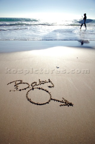 Funny amusing twist on Baby boy congratulations sign writing message on a sandy beach in Tarifa Spai
