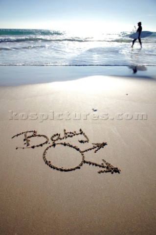 Funny amusing twist on Baby boy congratulations sign writing message on a sandy beach in Tarifa Spai