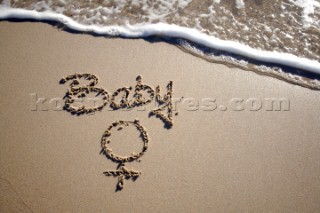 Baby girl sign writing message on a sandy beach in Tarifa, Spain, near Gibraltar.