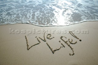 One Life - Live it sign writing message on a sandy beach in Tarifa, Spain, near Gibraltar.