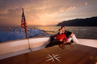 Lifestyle couple onboard a Vicem 72 classic motor yacht in the sunset Model Released.