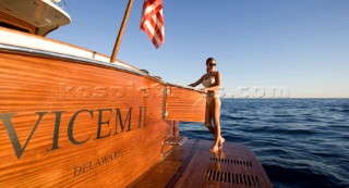Lifestyle female onboard a Vicem 72 classic motor yacht in swimsuit on swim platform about to take a swim Model Released.