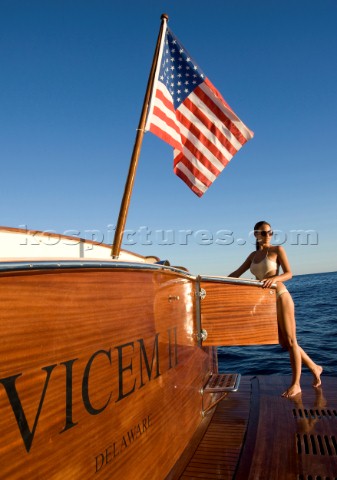 Lifestyle female onboard a Vicem 72 classic motor yacht in swimsuit on swim platform about to take a