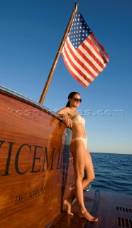 Lifestyle female onboard a Vicem 72 classic motor yacht in swimsuit on swim platform about to take a swim Model Released.