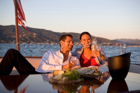 Lifestyle couple having drinks and coctails onboard a Vicem 72 classic motor yacht in the sunset Mod