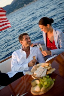 Lifestyle couple having drinks and coctails onboard a Vicem 72 classic motor yacht in the sunset Model Released.