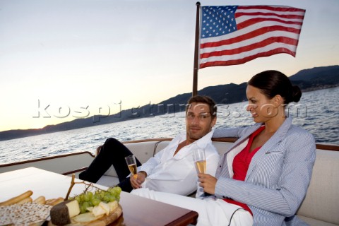 Lifestyle couple having drinks and coctails onboard a Vicem 72 classic motor yacht in the sunset Mod