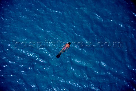 Lone female girl snorkelling on bright blue water in solitude