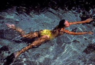 Girl swimming in the sea in yellow swimsuit bikini