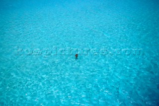 Romantic couple embrace swimming in an expanse of open turquoise sea in the Maldives