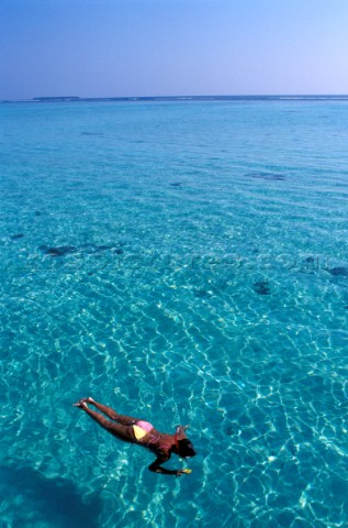 Girl female snorkelling on turquoise blue water in the Maldives
