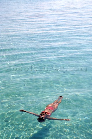 Girl relaxing lying floating on the surface of the turquoise sea water in the Maldives