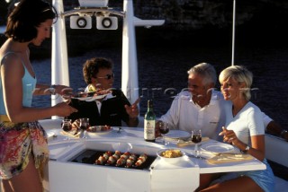 Couples enjoying a meal on deck of a Fairline powerboat