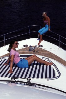 Two female models sitting on bow of Fairline powerboat
