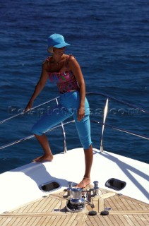 Female model in blue cap standing on bow of Fairline powerboat