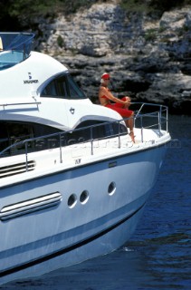 Model dressed in red on side deck of luxury power boat