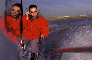 Man onboard fast powerboat using a handheld VHF radio