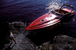 Romantic guy arriving in a fast red powerboat to collect sexy beautiful girl female model in a white swimsuit