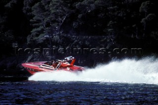 Girl sunbathing on the back of a speeding powerboat with rooster tail wash