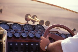 Detail of drivers arms behind wheel of a power boat