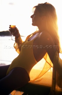 Woman wearing swimsuit drinking glass of champagne