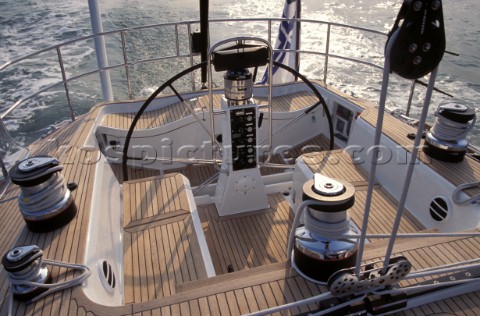 Wheel of Swan 68 under autopilot with teak deck and mainsheet blocks