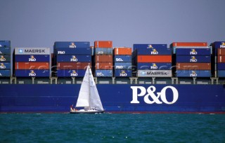 Sailing boat in shipping lane sailing passed container ship
