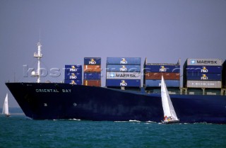 Sailing boat in shipping lane sailing passed container ship