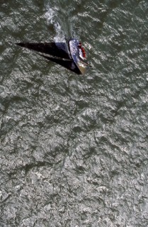Aerial shot of racing yacht casting shadow over water