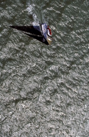 Aerial shot of racing yacht casting shadow over water