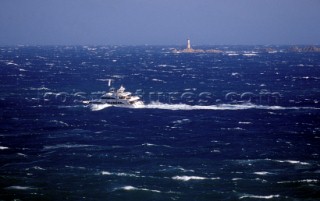 Superyacht My Way passes rocks and a lighthouse in huge rough breaking seas caused by a Mistral wind
