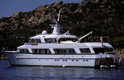 Cruising American superyacht at anchor in a quiet anchorage mooring with charter guests preparing to