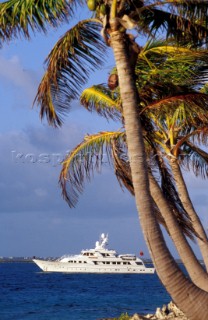 Cruising superyacht at anchor in a quiet anchorage mooring with palm trees