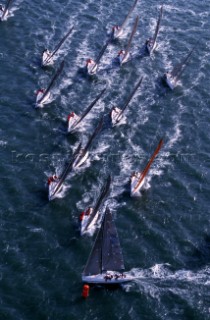 A ‘heart-in-the-mouth’ moment for the crew of American Farr 40 One Design yacht Predator as they approach the first windward mark during a Farr 40 World Championships. The big gamble they have taken is to approach the first mark in the clear wind on the left side of the race course, whilst the whole fleet approaches with right-of-way on starboard tack from the right. Predator’s precision is a winning move and she rounds two metres clear ahead of her competitors. In contrast a British yacht following her from the left is a few seconds too late and has to bear away and sail to the back of the fleet. After 30 minutes of racing, determining first and last place is a matter of one boat length..