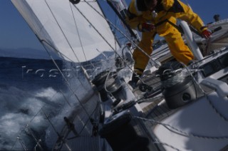 Close up of a man using a winch onboard a sailboat