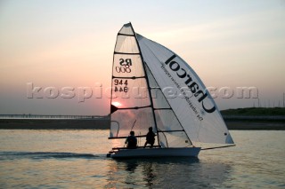RS800 dinghy sailing under asymmetric spinnaker at sunset on the Hamble River, UK