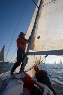 Man hoisting a jib to sail in a yacht race Round the Island Race on a J80 sportsboat