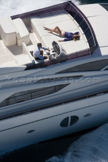 Man driving a powerboat and woman sunbathing.