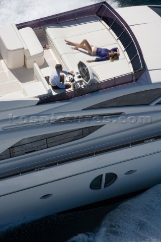 Man driving a powerboat and woman sunbathing
