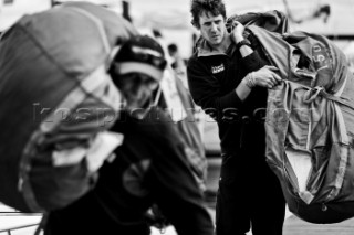 Crew carrying maxi sails Dockside. Rolex Fastnet Race 2011.