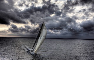The canting keel maxi yacht Alfa Romeo offshore in a storm with clouds and stormy sky during the La Giraglia Race