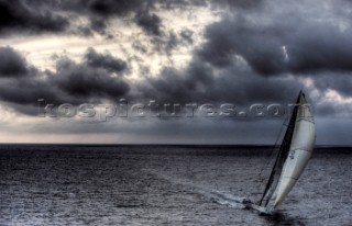 The canting keel maxi yacht Alfa Romeo offshore in a storm with clouds and stormy sky during the La Giraglia Race