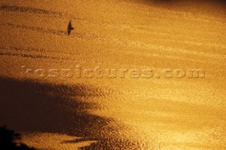 Tranquil silhouette of sailboat on ocean with golden sunset