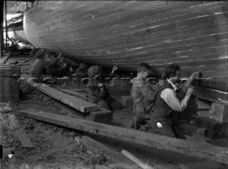 Caulking team work on a hull at Grove & Gutteridge yard in Cowes, Isle of Wight, in the 1930s