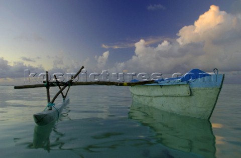 A traditional pacific canoe wonders the waters of Aitutaki Island during sunset Cook Islands South P