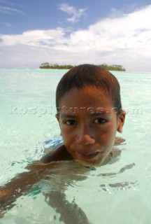 A young boy plays in the water off Honeymoon Island, Cook Islands, South Pacific.