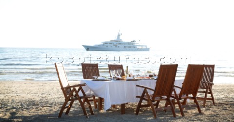 Dinner on the beach with superyacht White Cloud in the background