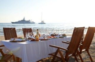 Dinner on the beach with superyacht White Cloud in the background