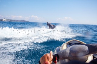Two men jet skiing in the mediterranean sea.